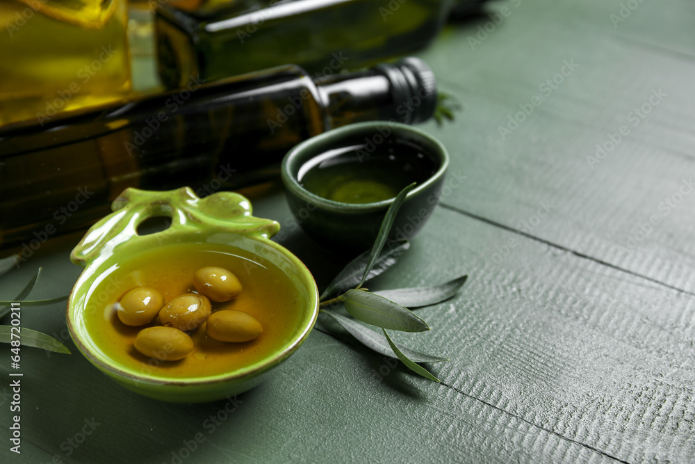 Bowls with fresh olive oil on green wooden background