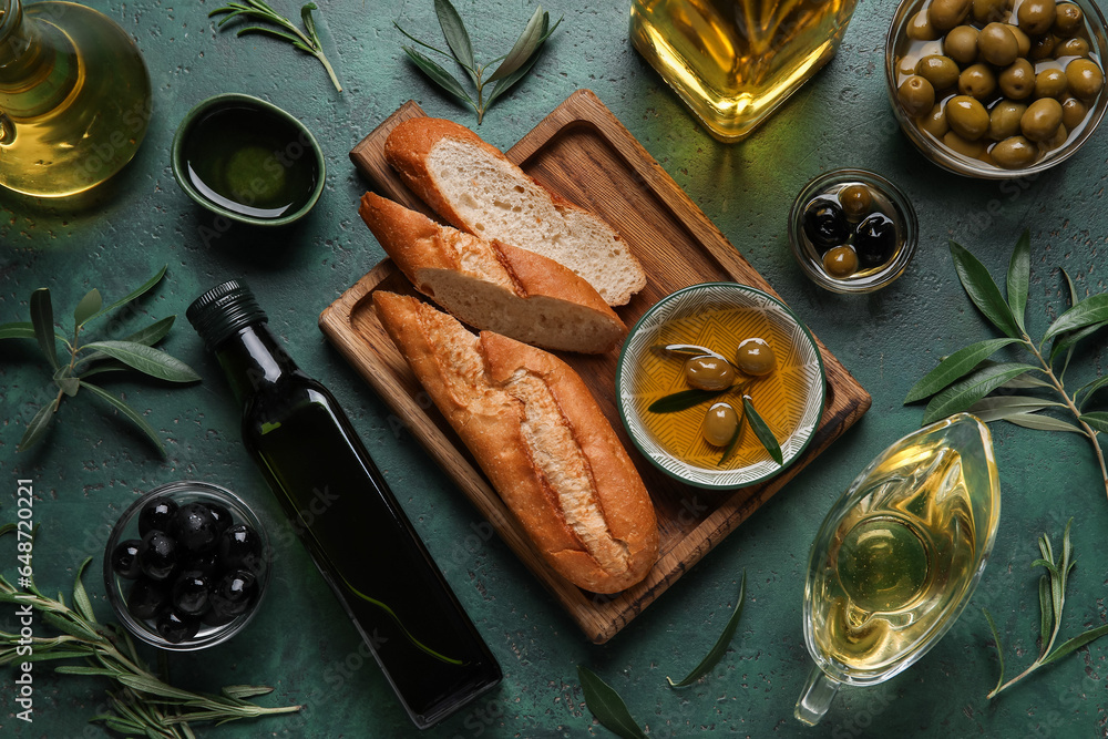 Bowls and different glassware of fresh oil, olives and bread on green background