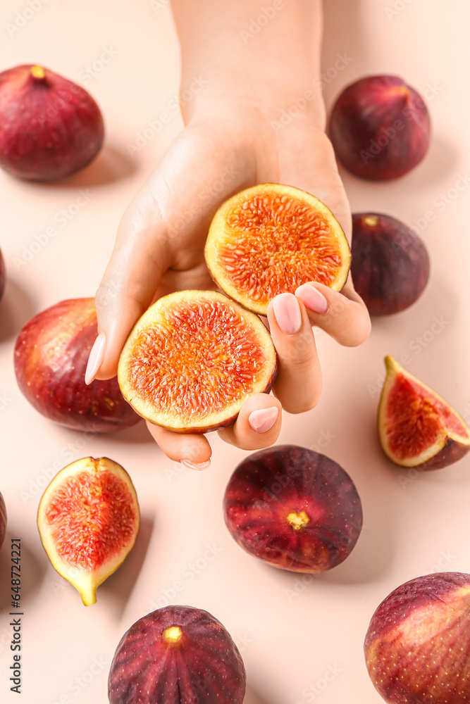 Female hands with slices of ripe fresh figs on pale pink background