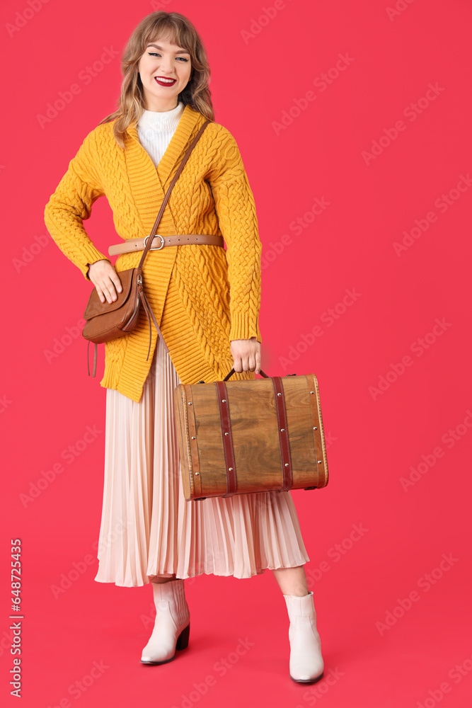 Stylish young woman in fall clothes with bag on red background