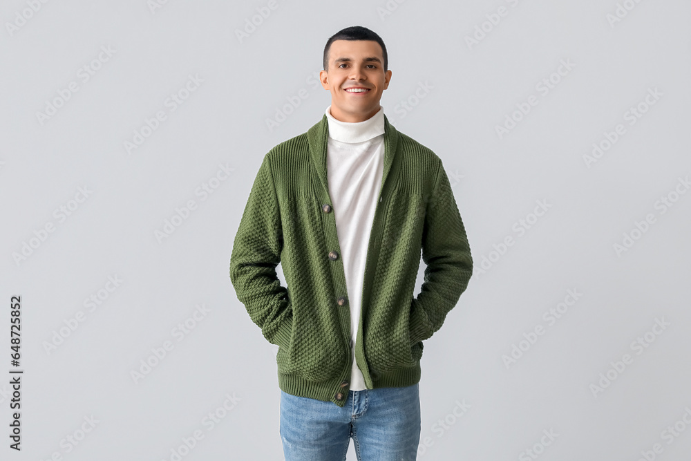 Young man in knitted sweater on light background