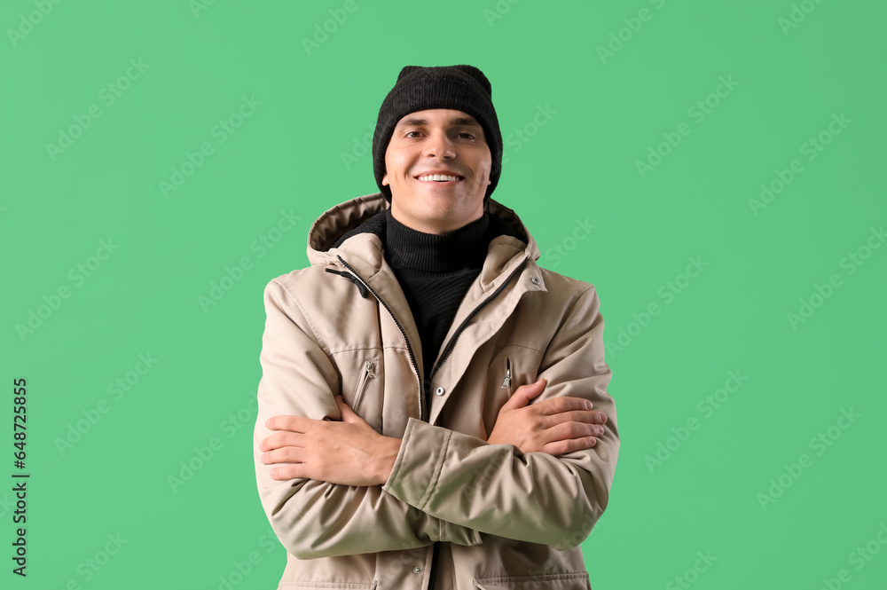 Young man in winter clothes on green background