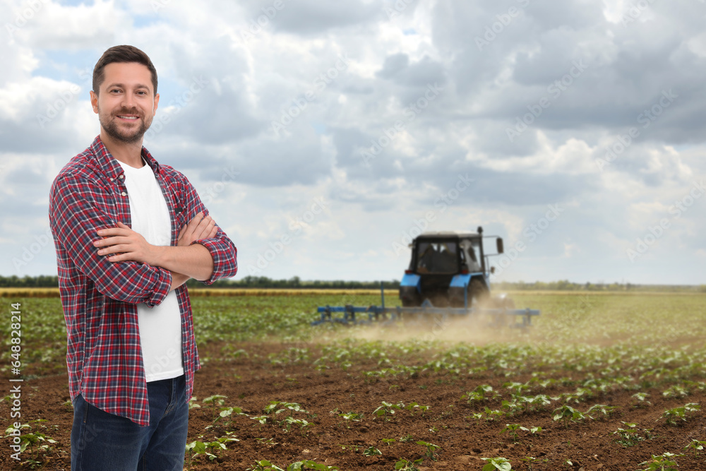 Confident farmer with crossed arms in field. Harvesting season