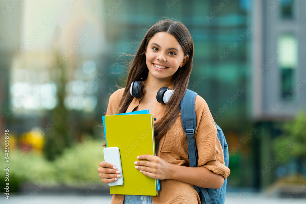 Cheerful beautiful woman student posing at university campus, copy space