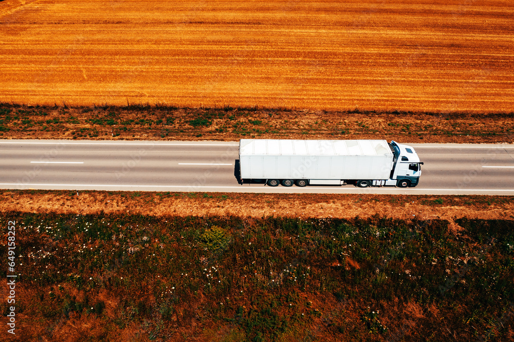 White truck on highway through countryside landscape, aerial shot