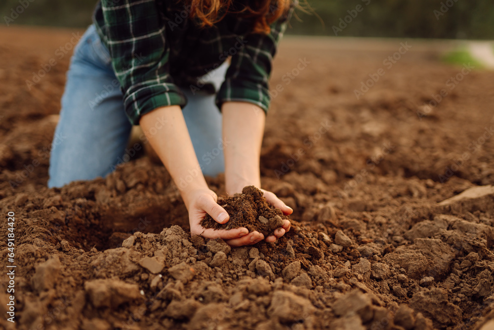 Close-up of female farmers hands holding compost, fertile black soil to test the quality and health of the soil before sowing. Nature, gardening concept.