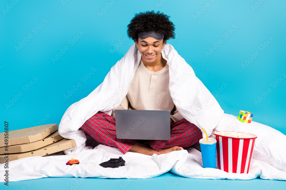 Full size portrait of positive barefoot person sit bed covered cozy blanket isolated on blue color background