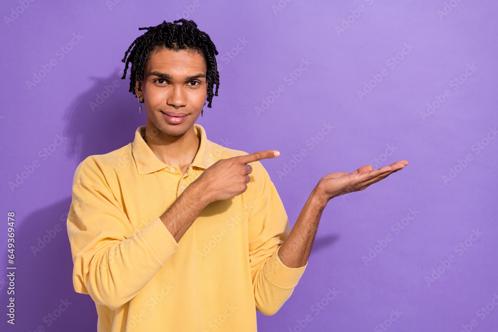 Photo of nice satisfied man wear stylish yellow clothes recommend novelty demonstrates empty space isolated on purple color background