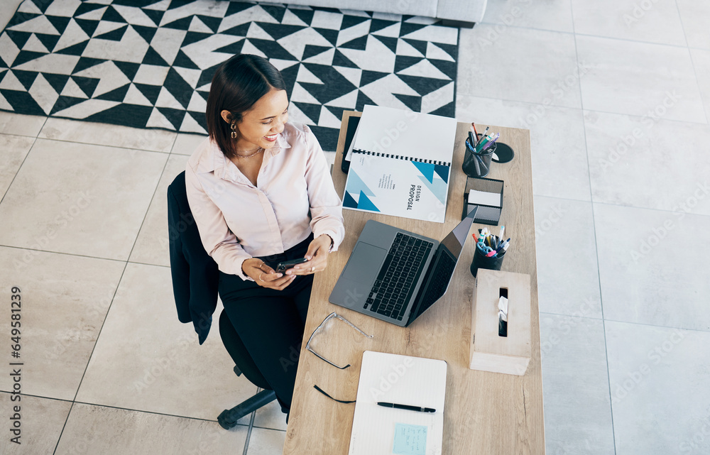 Smartphone, laptop and business woman at table in home living room on social media, research and freelancer typing. Happy designer on phone at desk, reading email and communication for remote work