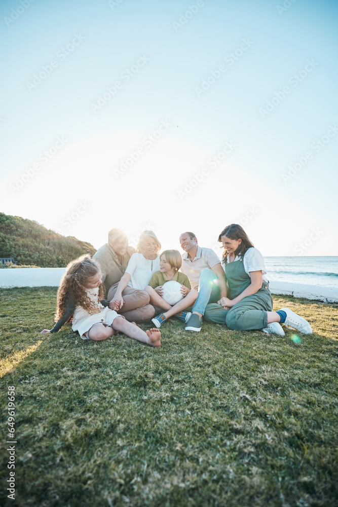 Family, grandparents and kids on grass by ocean for bonding, relationship and relax together. Nature, parents and happy grandmother, grandfather and children on holiday, vacation and travel by sea