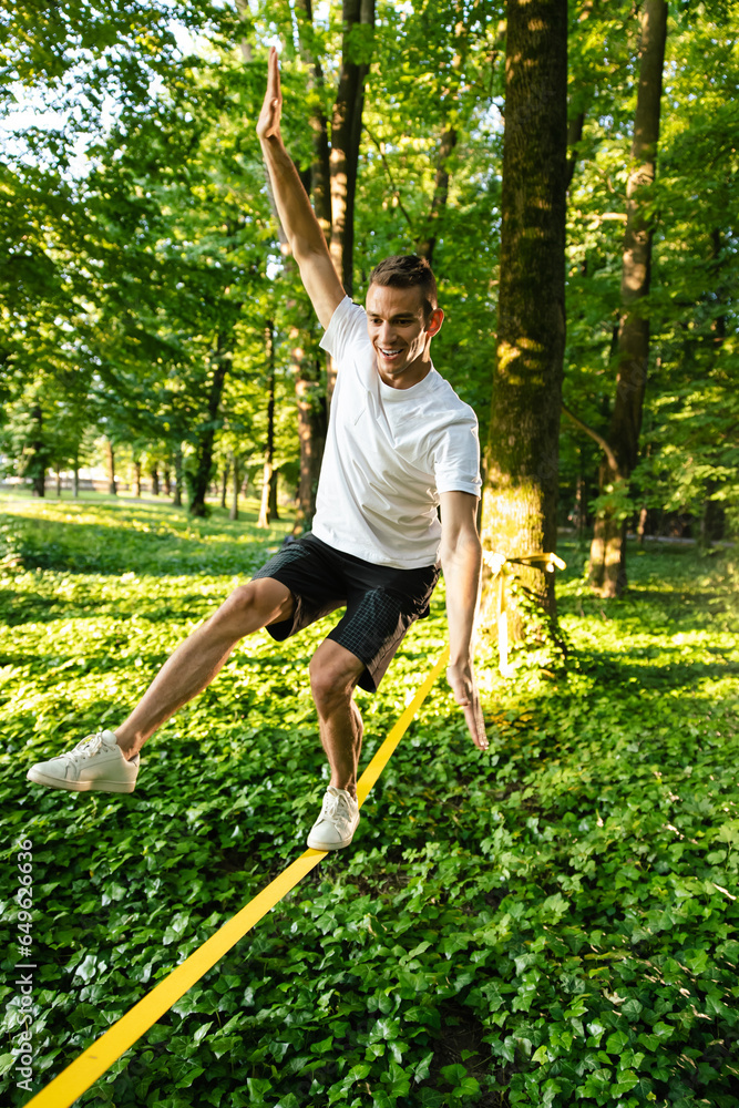 Young man in white tshirt and shorts on the rope keeping balance