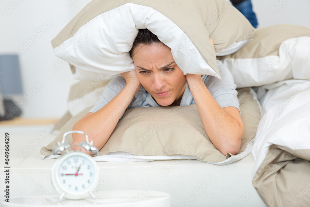 young woman covering her head with a pillow