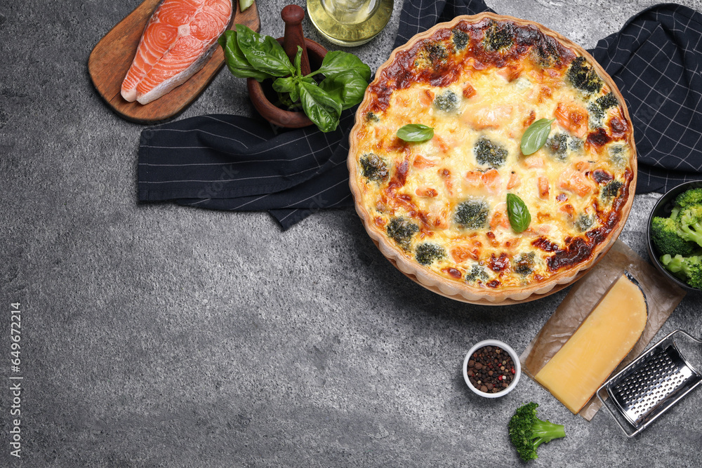 Delicious homemade quiche and ingredients on gray table, flat lay. Space for text