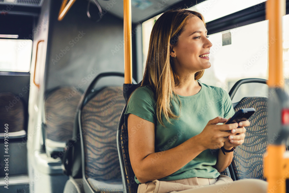 Young woman checking social media on phone in bus. Beautiful girl with long hair using smartphone for reading or writing message while standing in city bus.