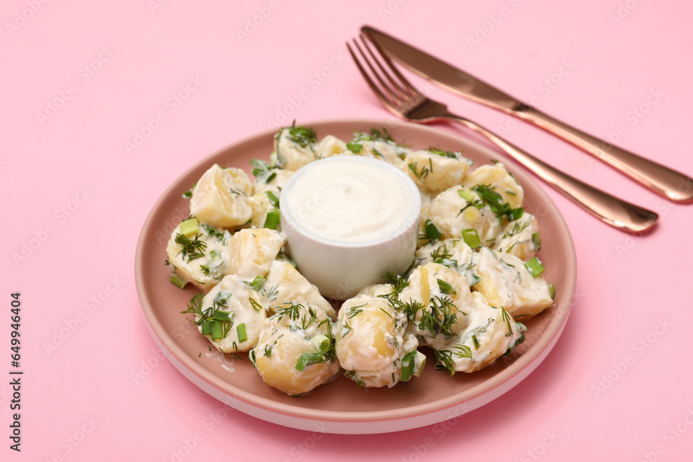 Plate of tasty Potato Salad with greens on pink background