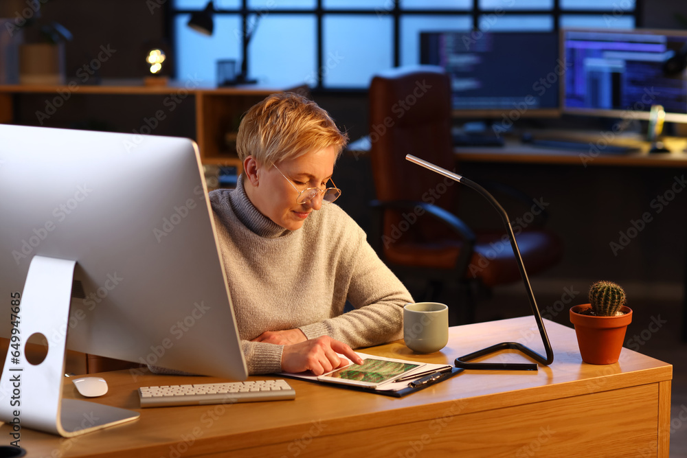 Mature female programmer working in office at night