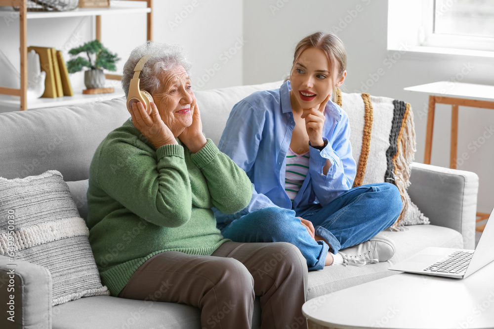 Young woman and her grandmother in headphones at home