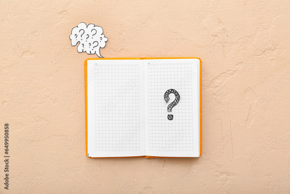 Notebook and speech bubble with question marks on beige background