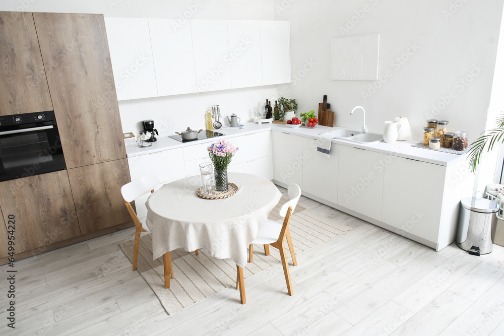 Interior of modern kitchen with flowers on dining table