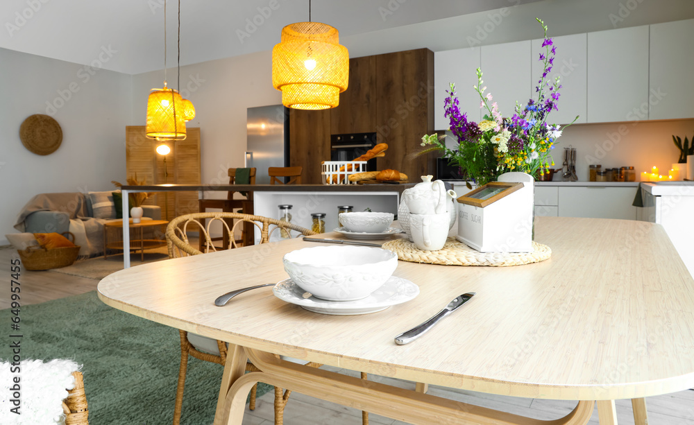 Dining table served with bowls and cutlery in interior of modern kitchen