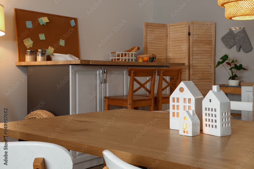 Wooden dining table with decorative candle holders in kitchen at evening, closeup