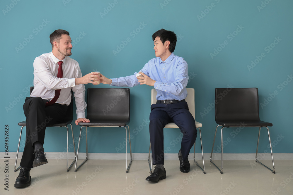 Male applicants with coffee waiting for job interview in room