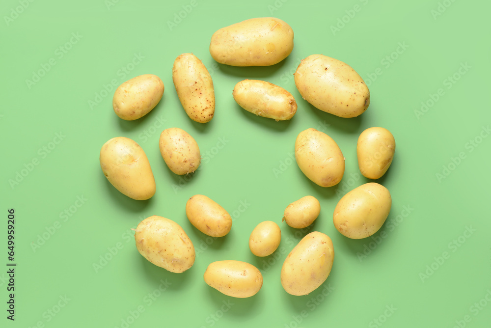 Frame made of raw potatoes on green background