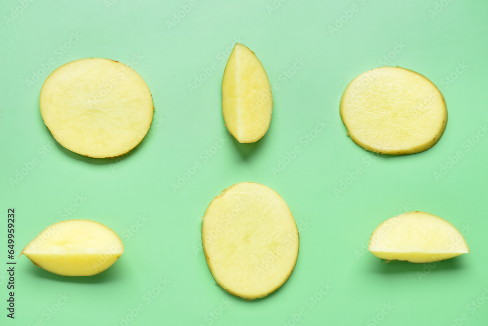 Pieces of raw potato on green background