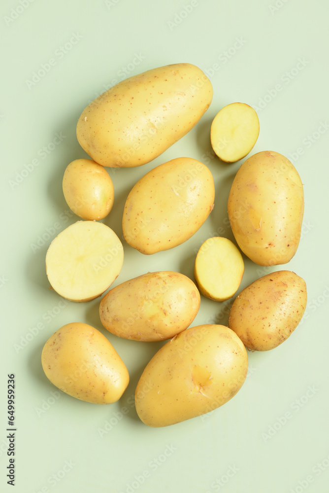 Raw potatoes on green background