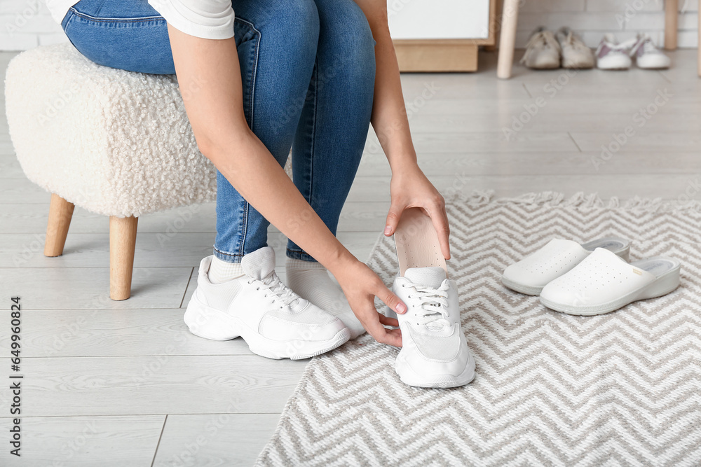 Woman putting orthopedic insole into sneaker at home