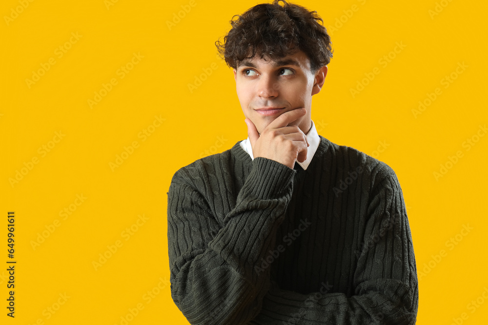 Portrait of pondering young man on orange background