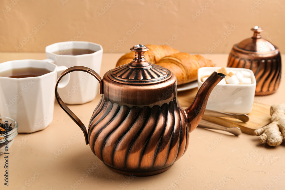 Stylish teapot, cups of tea, sugar and croissants on color background