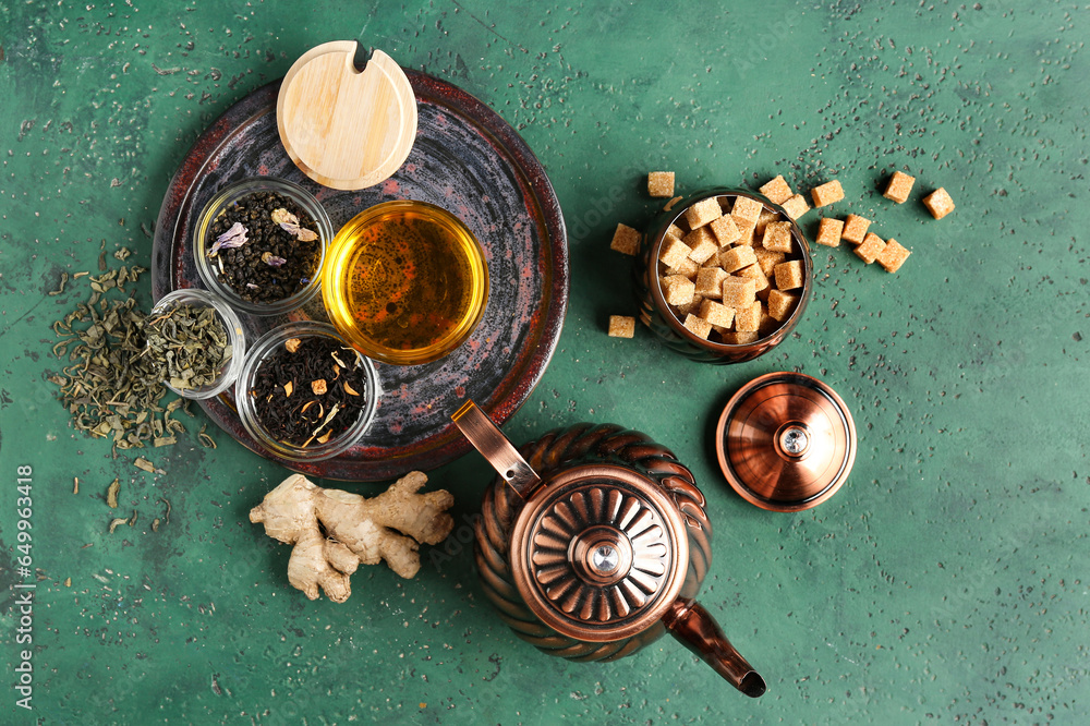 Composition with vintage brass tea set and different types of tea on green table