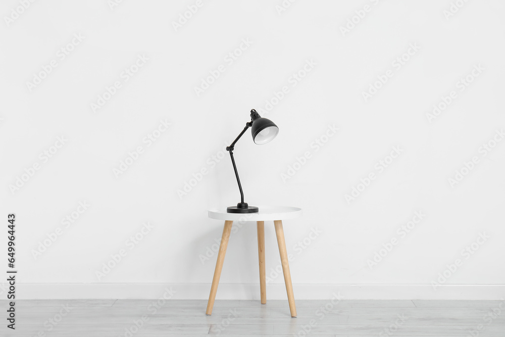 Desk lamp on small table near white wall