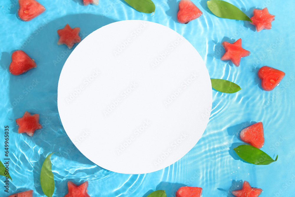 Blank card and pieces of fresh watermelon with leaves in water on blue background