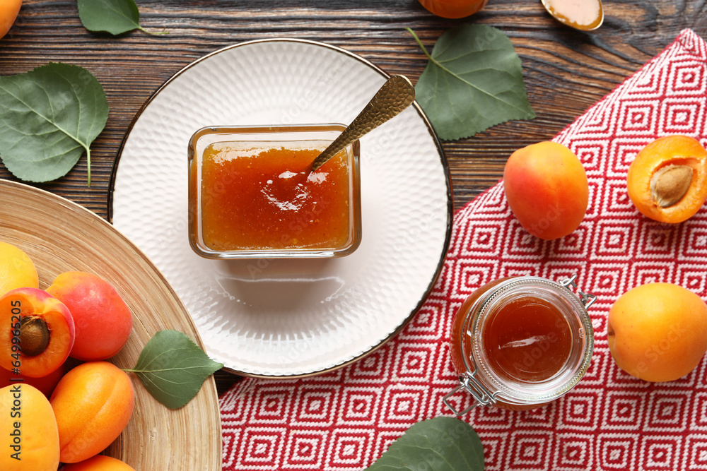 Glass bowl and jar with sweet apricot jam on wooden background