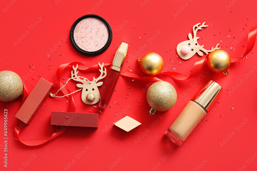 Composition with decorative cosmetics and Christmas decor on red background