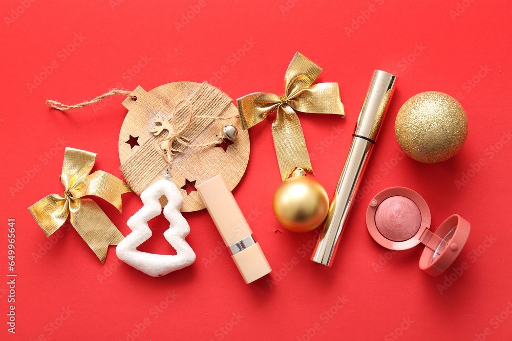 Composition with makeup products and Christmas decor on red background