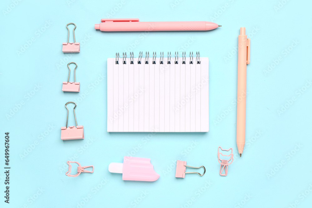 Notebook with different stationery supplies on blue background