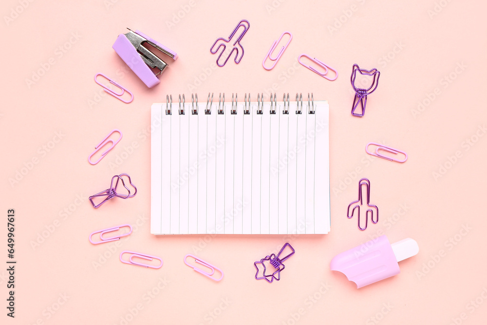 Notebook with different stationery supplies on pink background