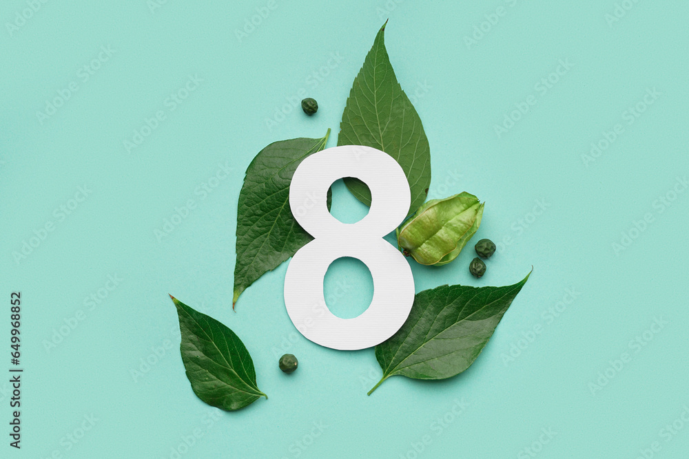 Green leaves with paper number eight on turquoise background