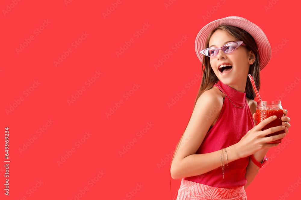 Little girl with glass of juice on red background