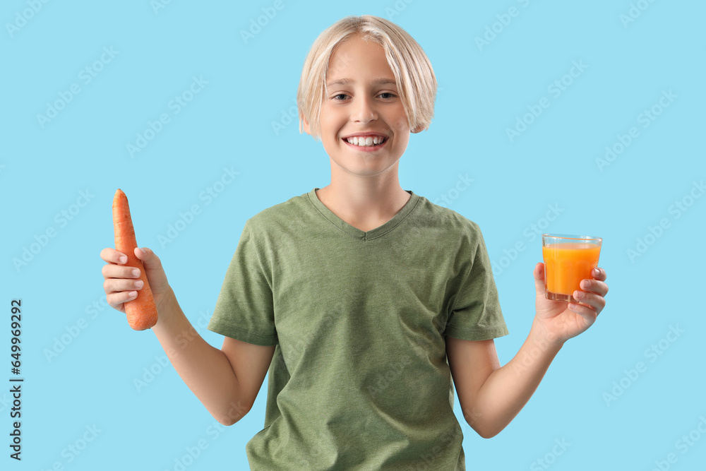 Little boy with glass of juice and carrot on blue background