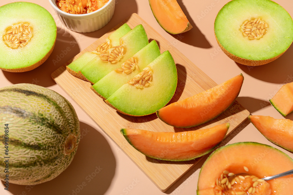 Wooden board with tasty ripe melons on orange background