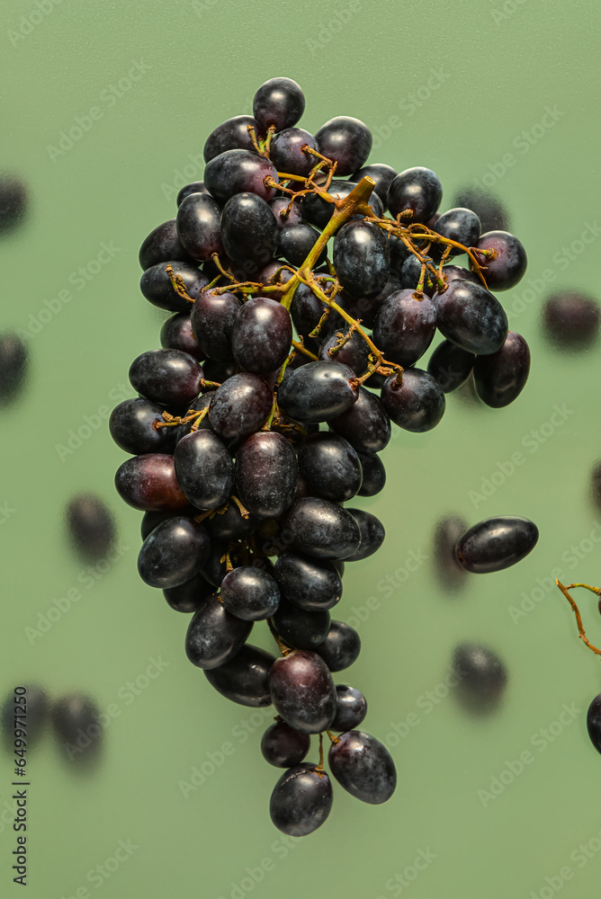 Flying sweet black grapes on green background