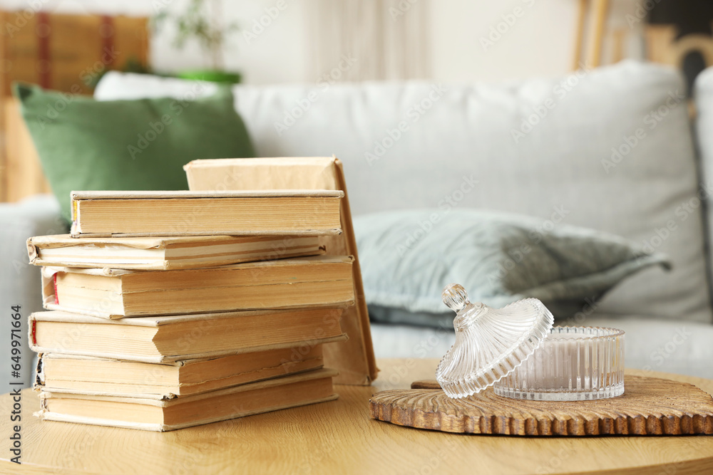 Stack of books and candle holder on wooden coffee table in living room, closeup