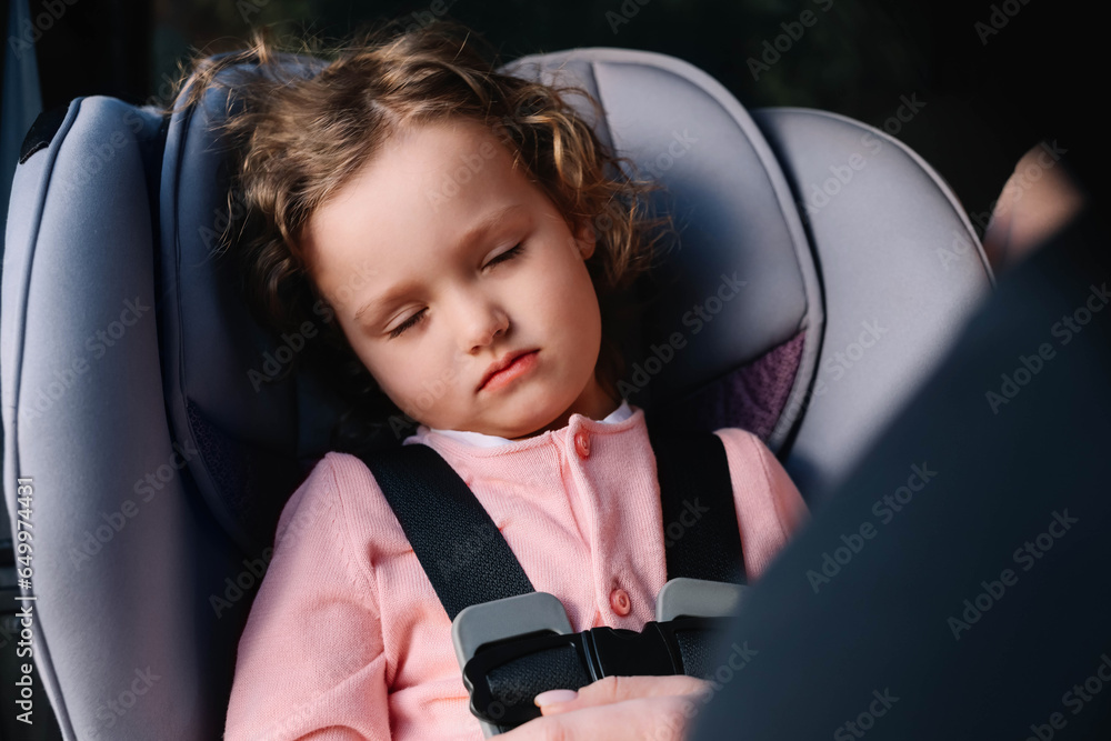 Cute little girl sleeping in child safety seat inside car