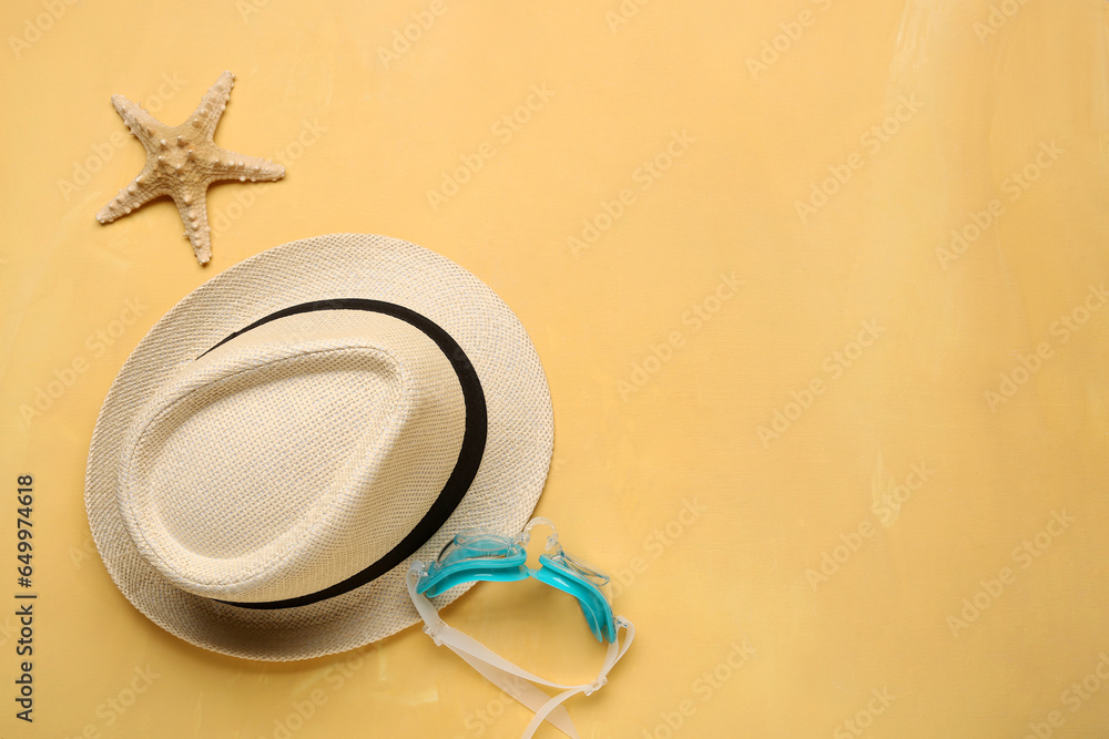 Stylish hat, goggles and starfish on color background