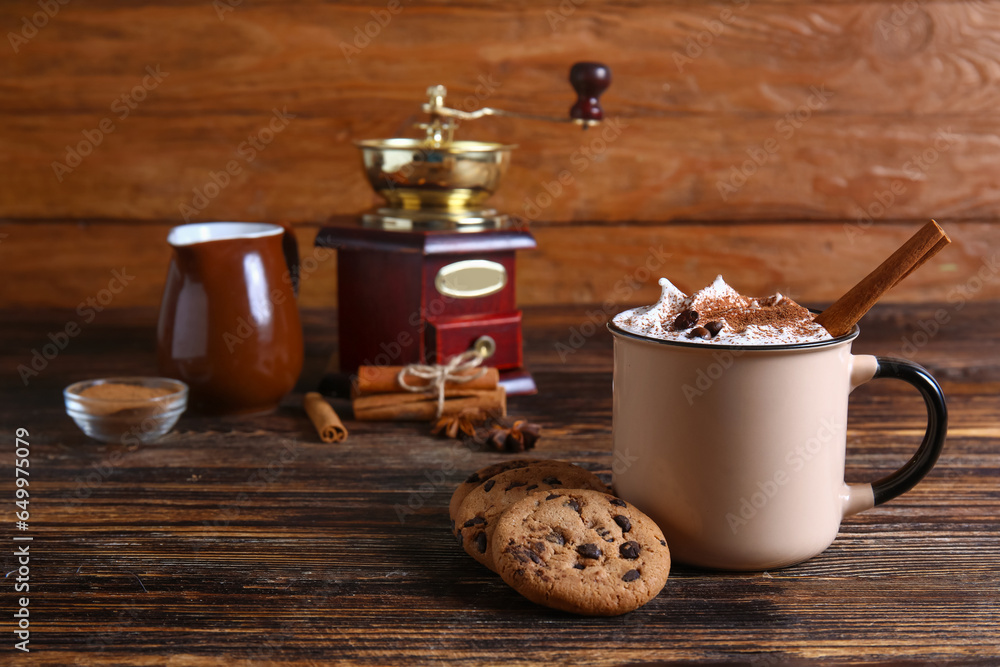 Mug of tasty coffee with cinnamon and cookies on wooden background