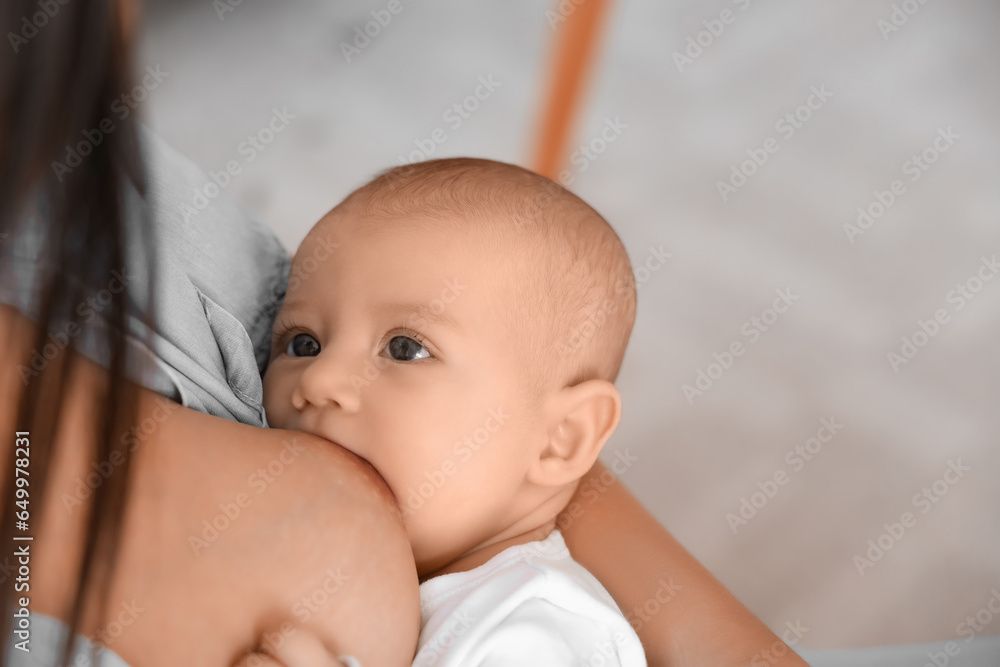 Young woman breastfeeding her baby at home, closeup